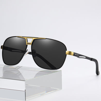 Sunglasses with gold frame and black lenses on a reflective surface