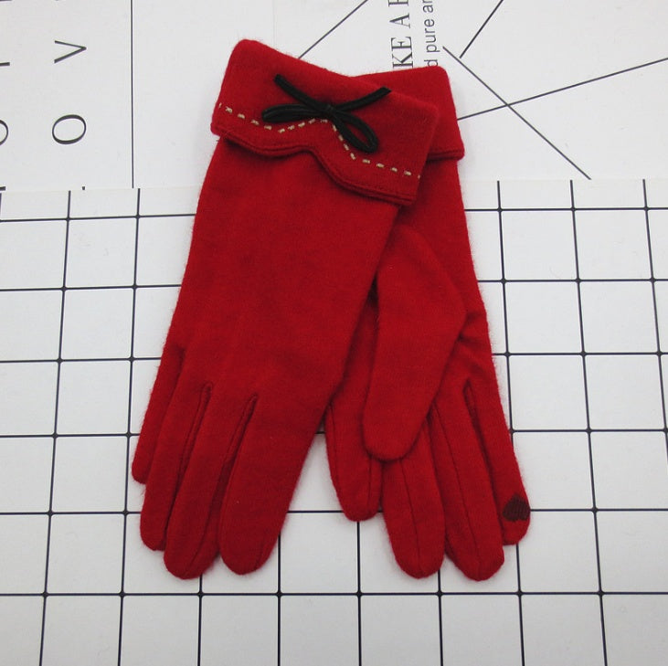 Red winter gloves with stitched cuff flap and black bow at the wrist