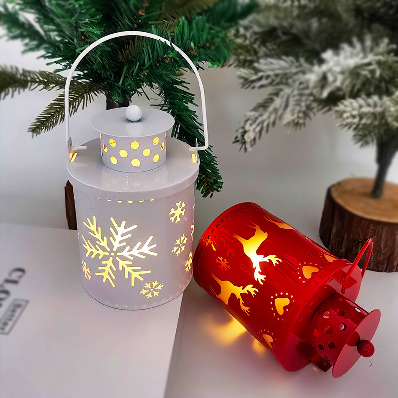 Decorative lanterns with snowflake and reindeer designs on a surface with a Christmas tree in the background.