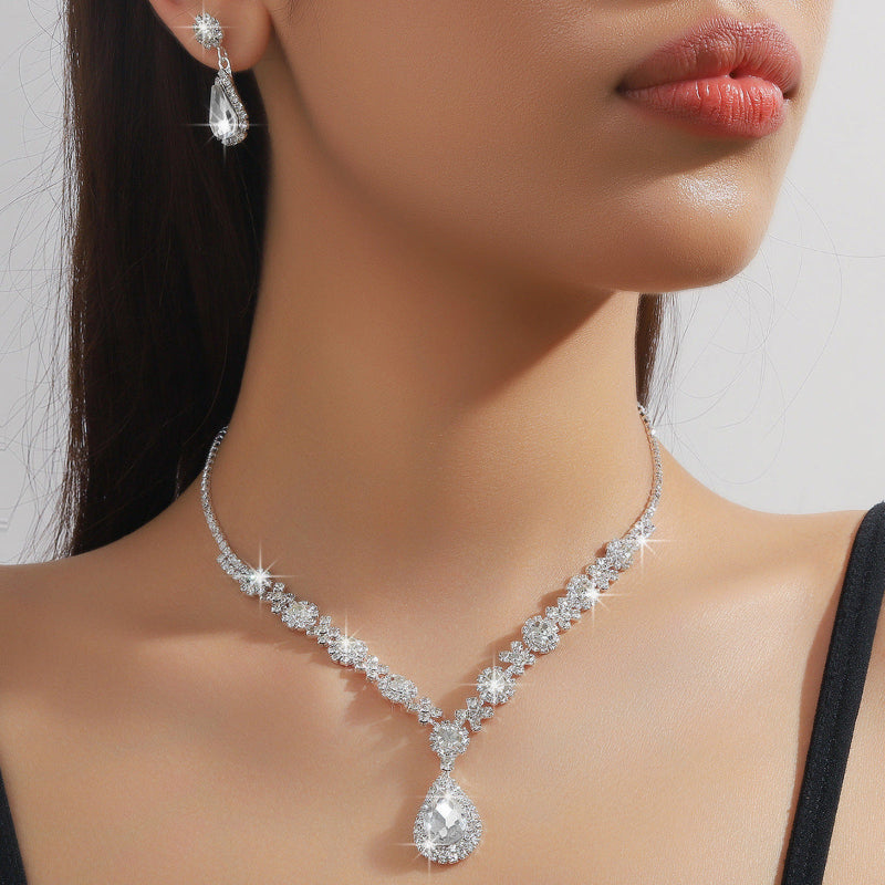 Close-up of a woman wearing a sparkling diamond necklace and earrings on a neutral background