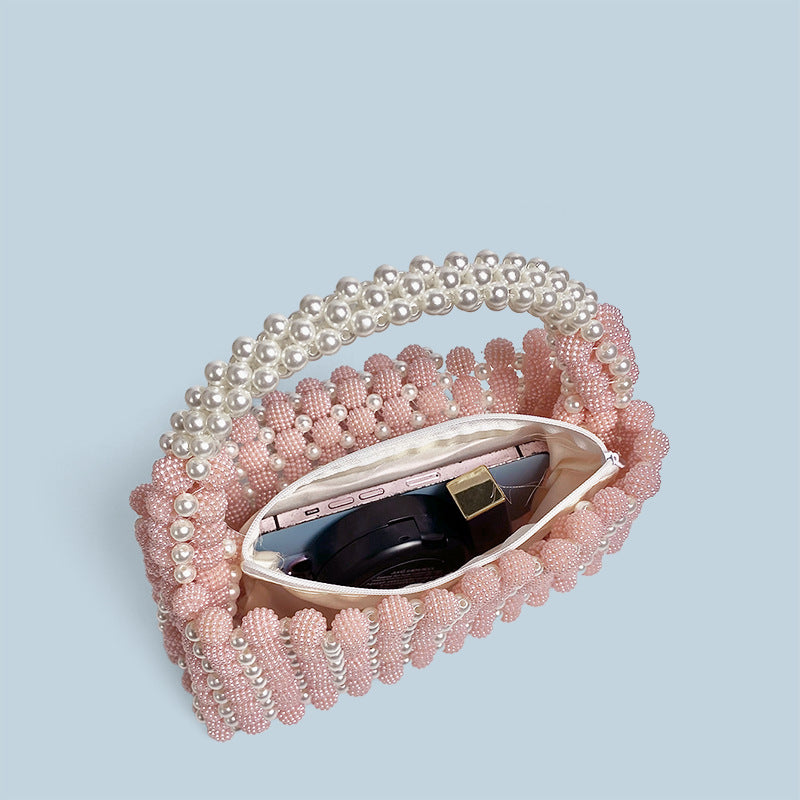 Pink beaded handbag with a mirror on a light blue background