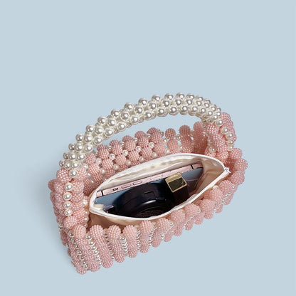 Pink beaded handbag with a mirror on a light blue background