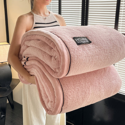 Person holding a pink blanket with a brand label indoors.