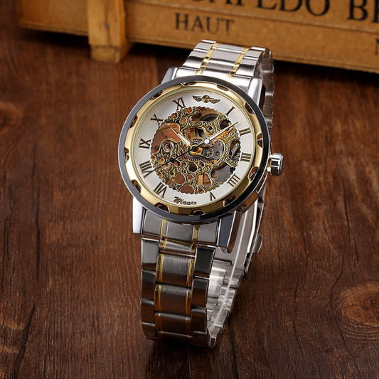 Silver and gold watch with intricate design on a wooden surface