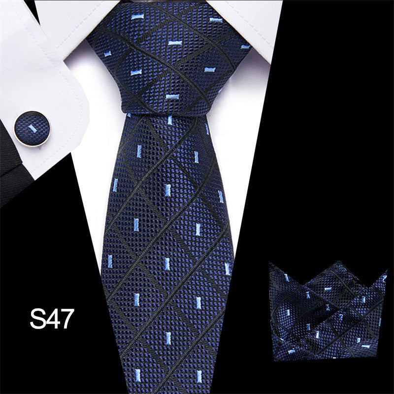 Navy patterned tie with matching pocket square and cufflinks on a white shirt.