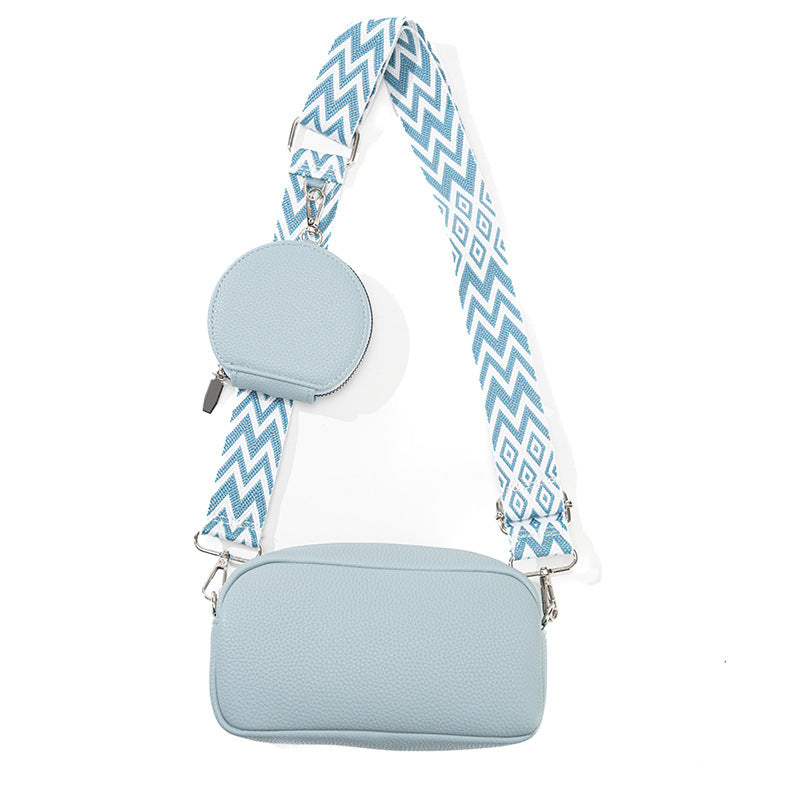 Light blue crossbody bag with a patterned strap on a white background