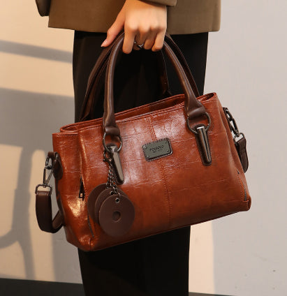 Brown large-capacity handbag with top handles, front zipper pocket, and crossbody shoulder strap