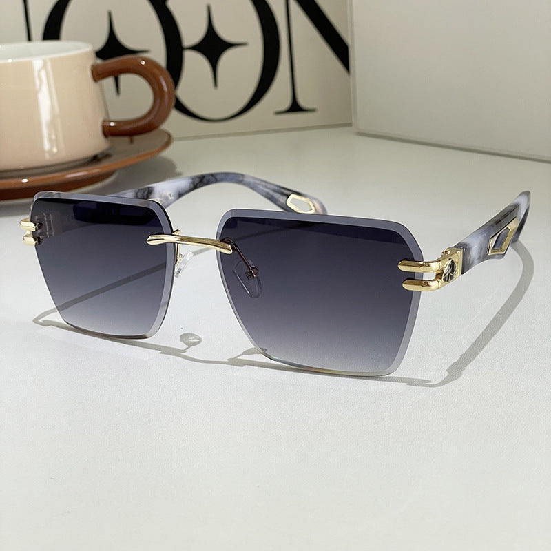 Sunglasses with gold accents on a light surface, with a cup and saucer in the background.