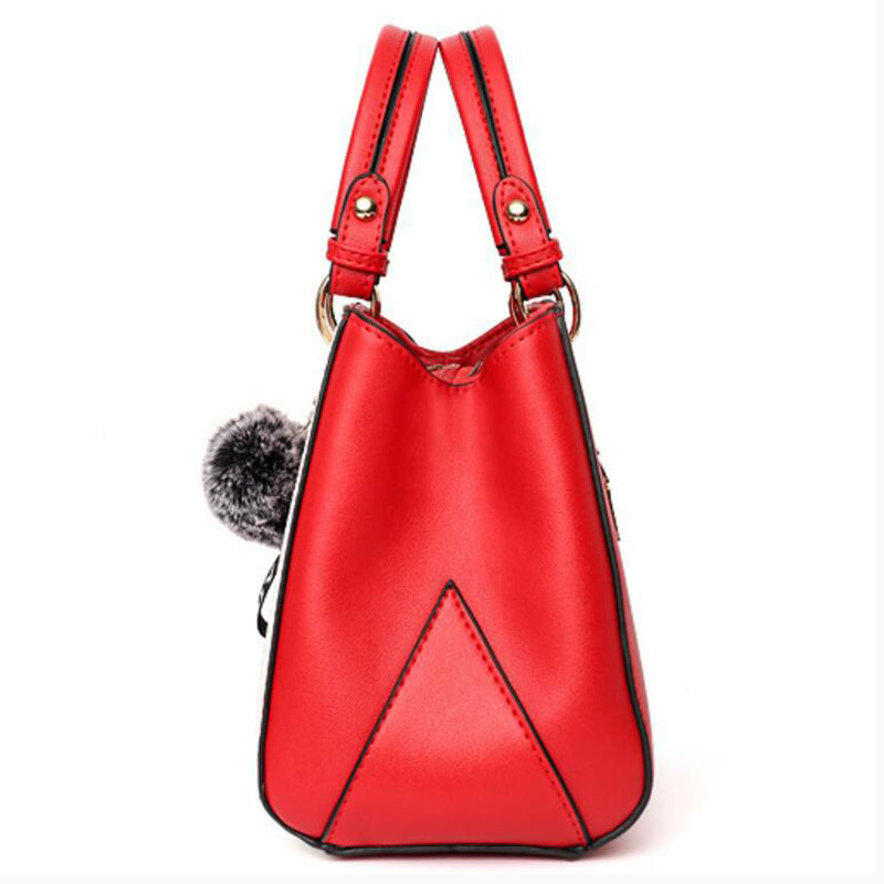 Red handbag with a pom-pom detail on a white background