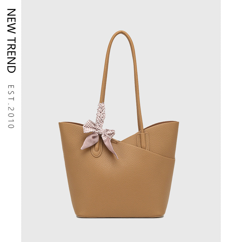Tan handbag with a decorative bow on a light gray background, featuring 'NEW TREND' branding.