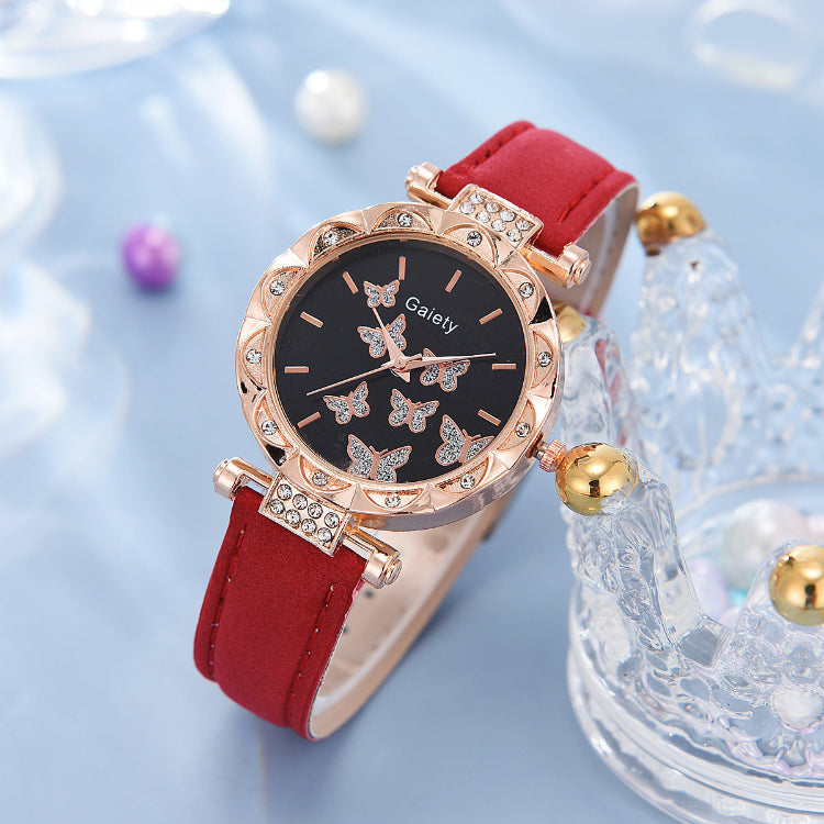 Wristwatch with red strap and rose gold case on a light blue background