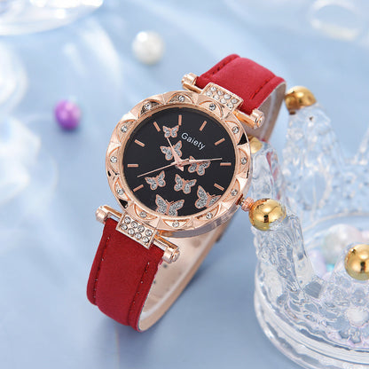 Wristwatch with red strap and rose gold case on a light blue background