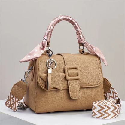 Beige handbag with pink handle and strap on a light gray background