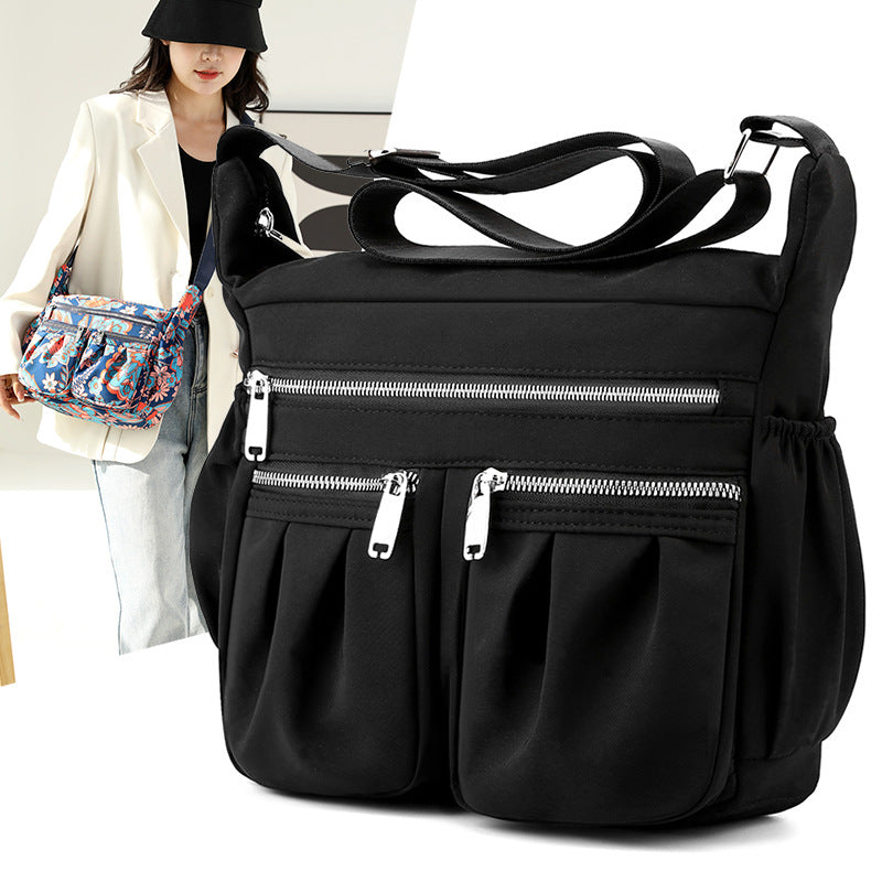 Large-capacity crossbody bag in solid black with front zip pocket and adjustable strap.