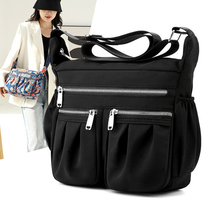 Large-capacity crossbody bag in solid black with front zip pocket and adjustable strap.