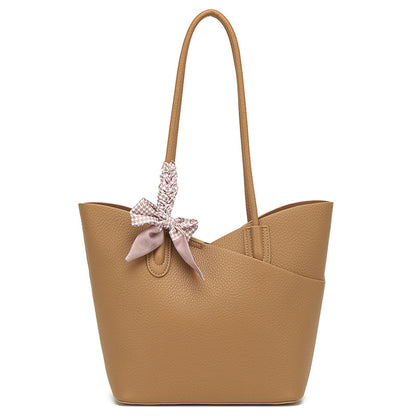 Tan handbag with a decorative bow on a white background
