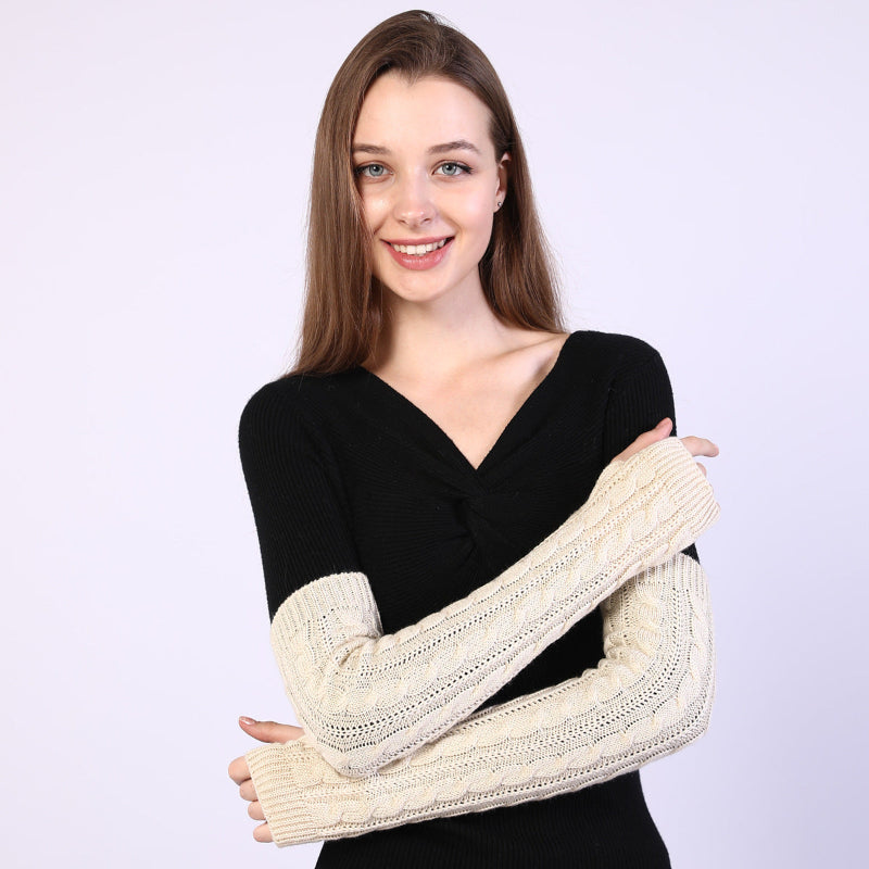 Woman wearing a black top and cream arm warmers against a white background