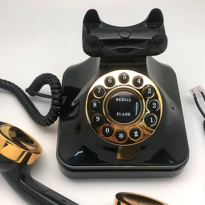 Black antique rotary telephone with gold dial and handset on top, front view