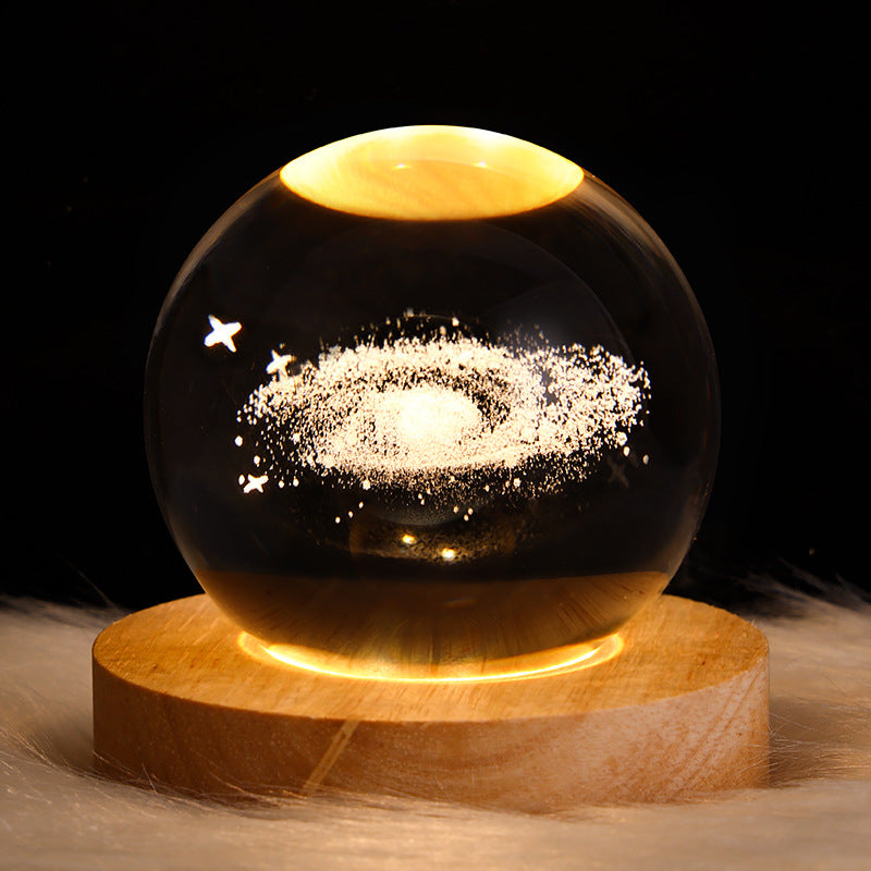 Glass sphere with celestial design on a wooden base against a dark background