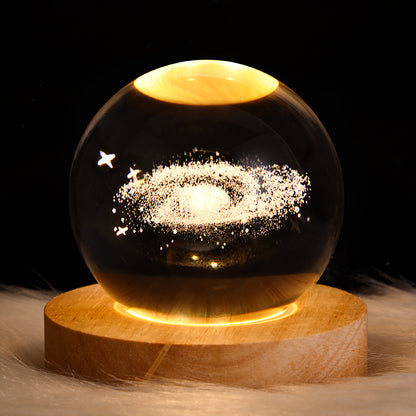 Glass sphere with celestial design on a wooden base against a dark background