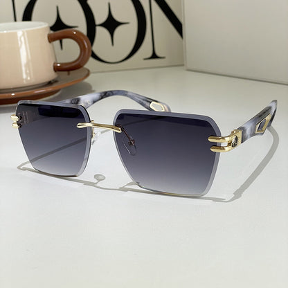Sunglasses with gold accents on a light surface, with a cup and saucer in the background.