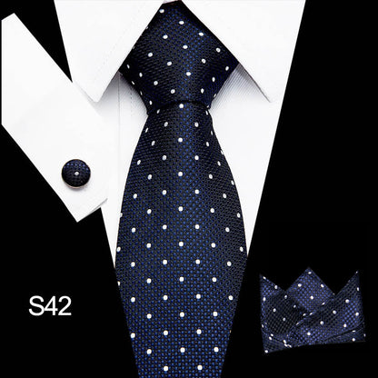Navy blue tie with white polka dots, matching pocket square, and cufflink on a white shirt.