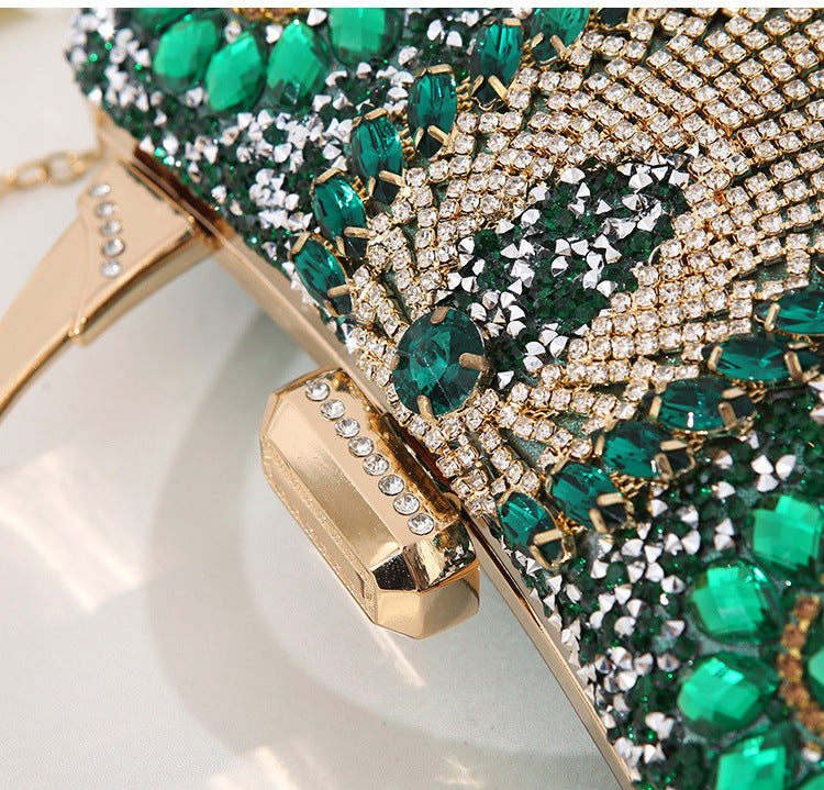 Elegant clutch bag with green gemstones and gold accents on a white background