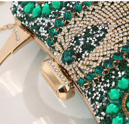 Elegant clutch bag with green gemstones and gold accents on a white background