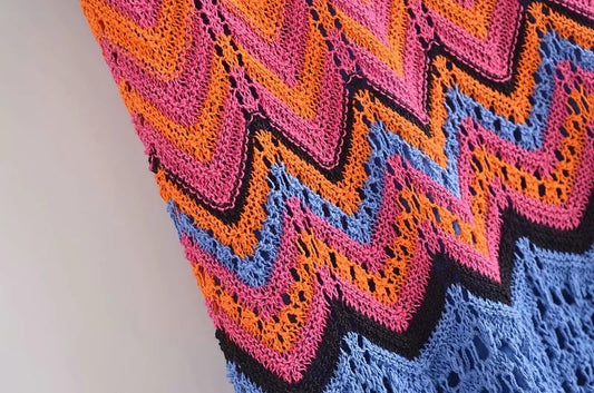 Colorful crocheted blanket with zigzag pattern on a plain background