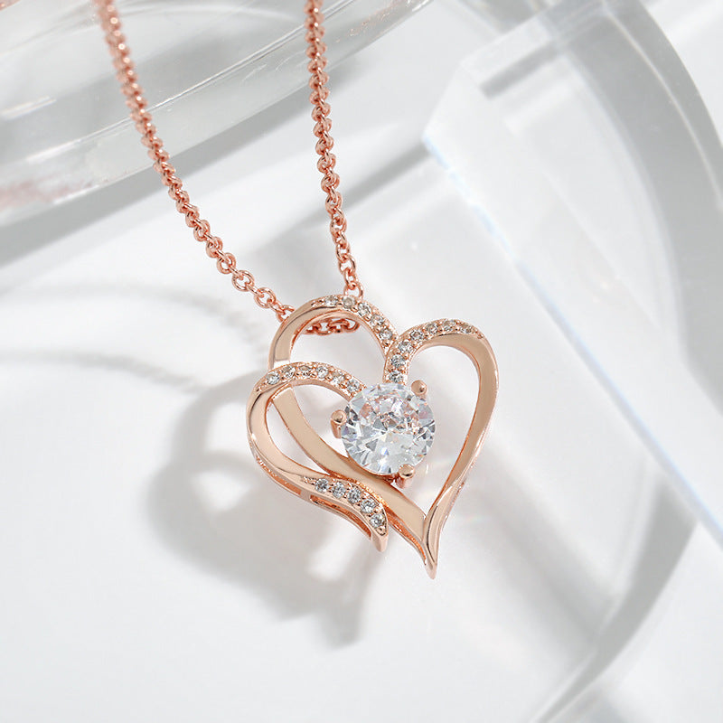 Rose gold heart-shaped necklace with a central gemstone on a light background