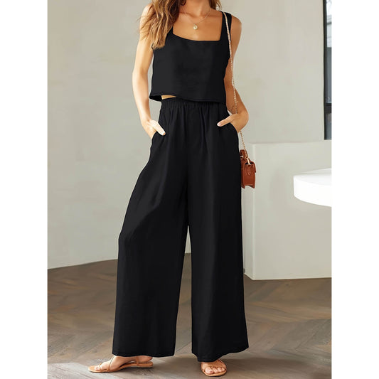 Woman wearing a black jumpsuit standing indoors with a neutral background