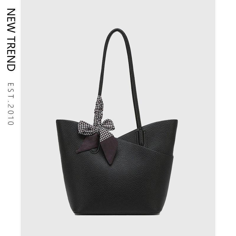 Black handbag with a decorative bow on a light gray background