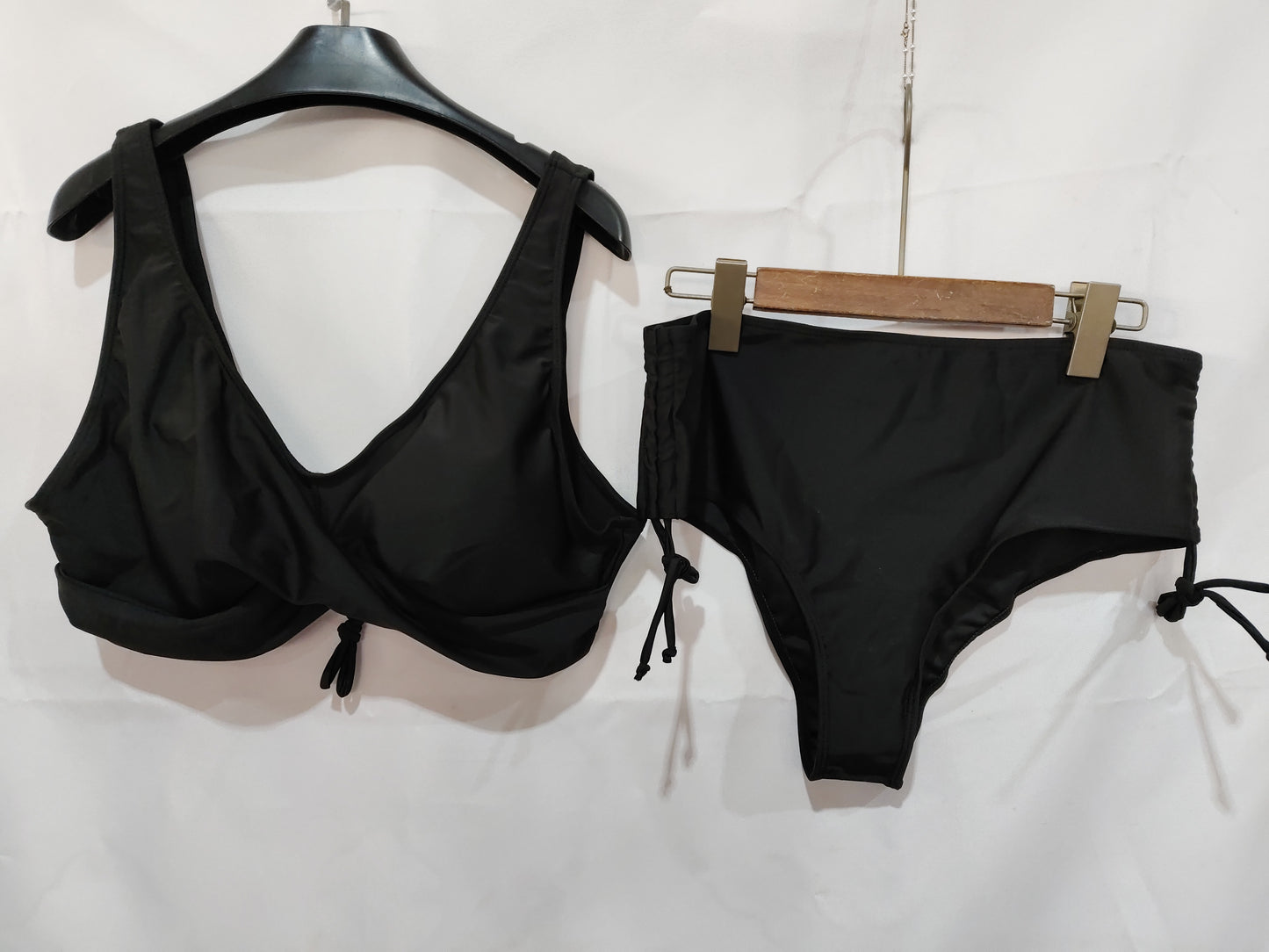 Black bikini set on hangers against a white background