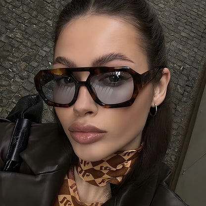 Woman wearing sunglasses and a patterned scarf with a textured wall background
