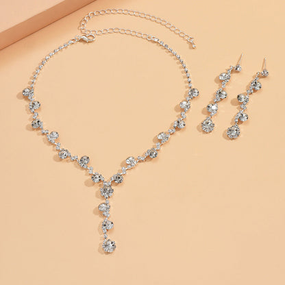 Silver necklace and earrings set on a beige background