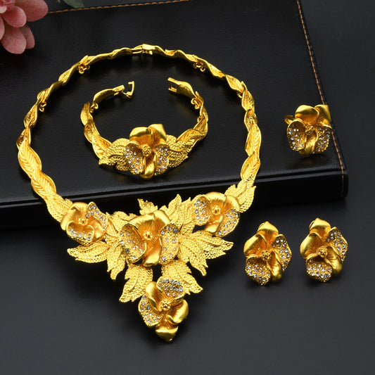 Gold jewelry set with necklace, bracelet, and earrings on a black background