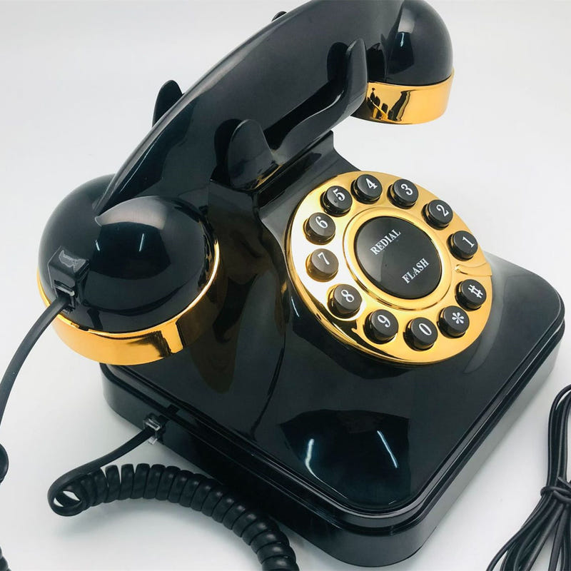 Black antique rotary telephone angled view with gold receiver and dial