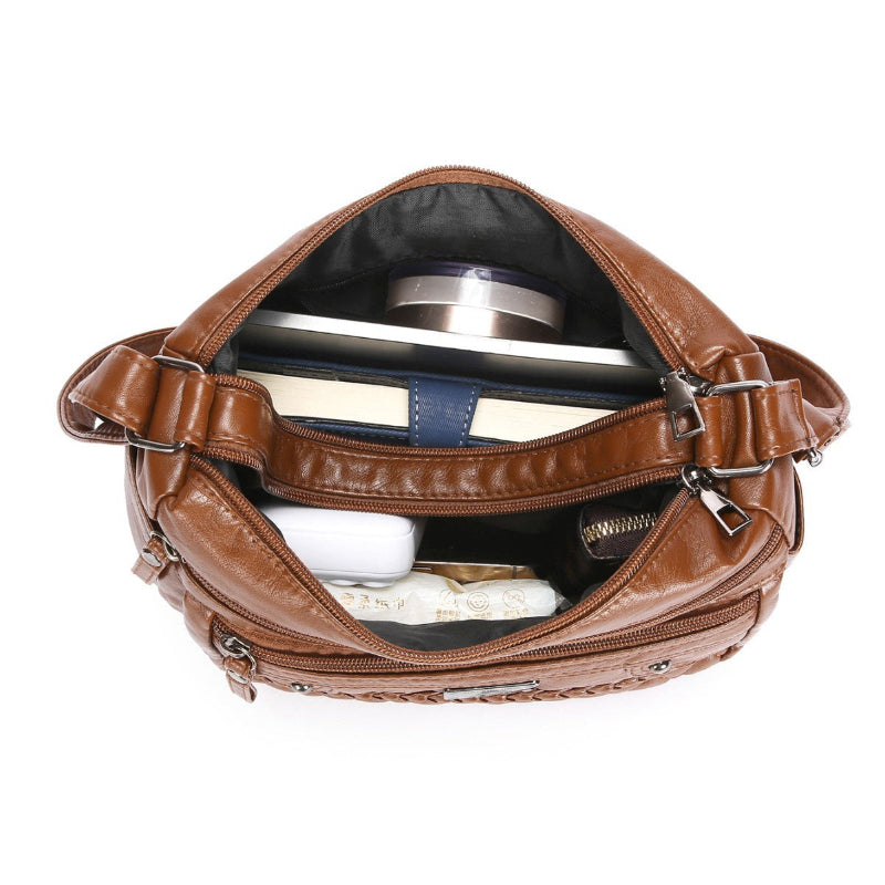 Brown leather bag with items inside on a white background