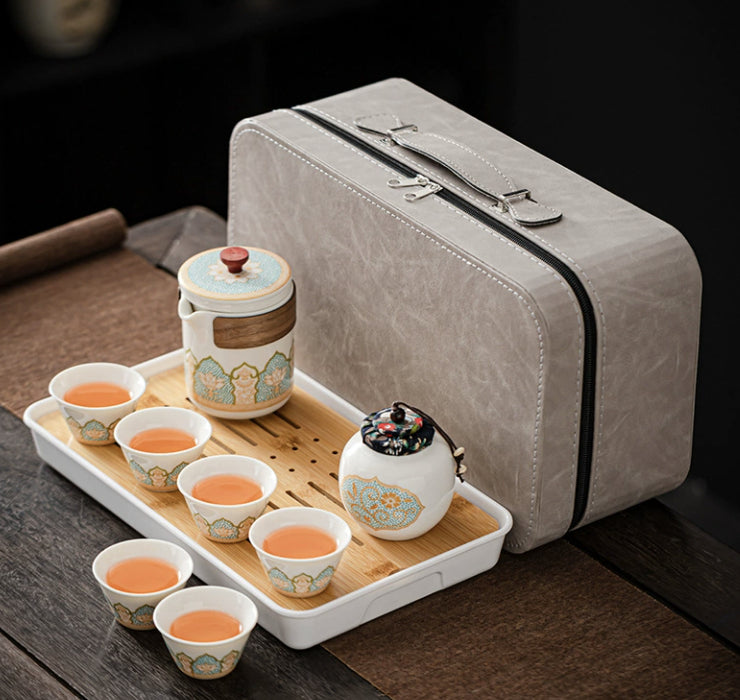 Tea set with cups and a teapot on a tray next to a gray carrying case.