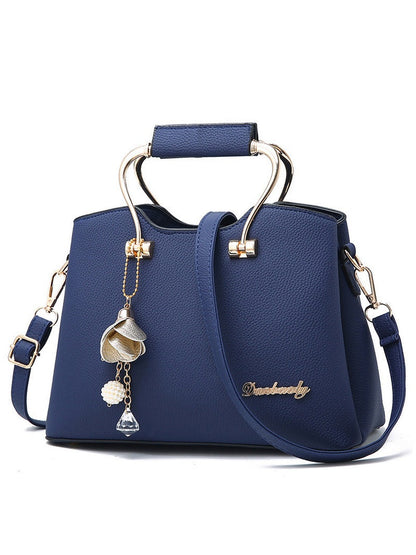 Blue handbag with decorative elements and a brand name on a white background