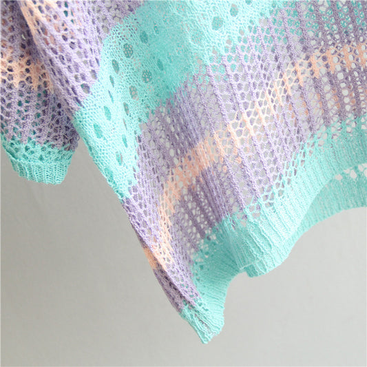 Knitted shawl with a gradient of purple, green, and orange on a light gray background