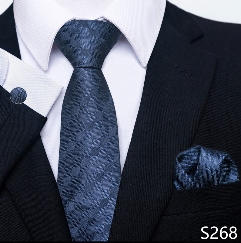 Black suit with a blue patterned tie and pocket square on a white shirt.