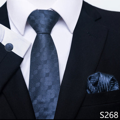 Black suit with a blue patterned tie and pocket square on a white shirt.