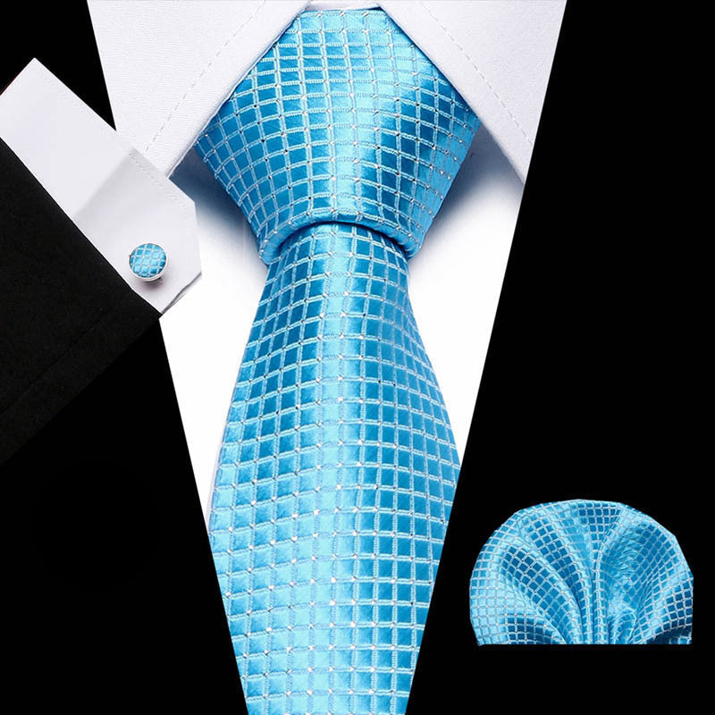 Blue patterned tie set with matching pocket square and cufflinks on a black and white background.