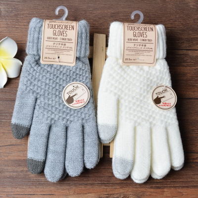 Pair of touchscreen gloves with gray and white color options on a wooden surface.