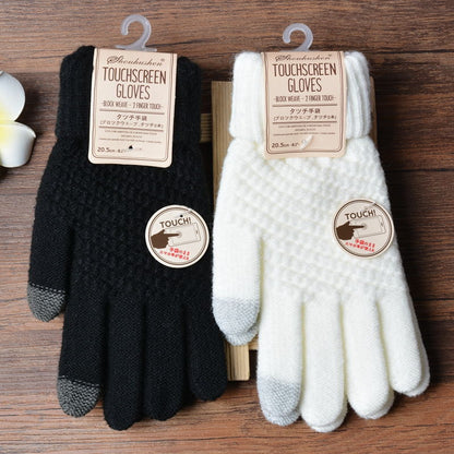 Black and white touchscreen gloves with labels on a wooden surface