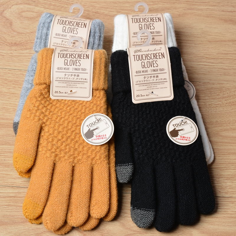 Pair of touchscreen gloves in yellow and black with labels on a wooden surface