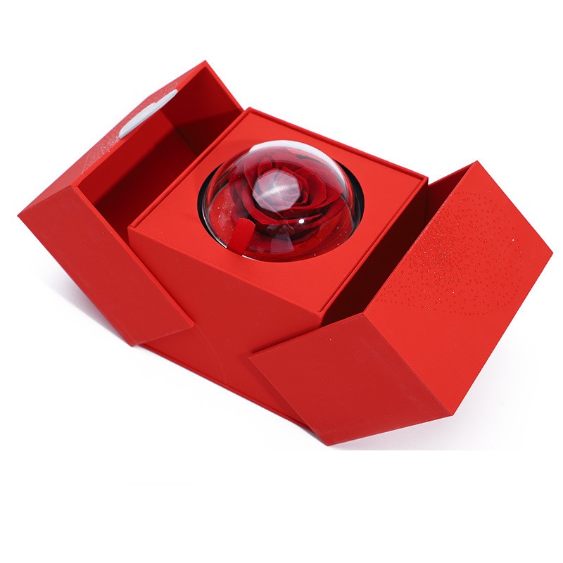 Red gift box open with clear glass dome containing a red rose