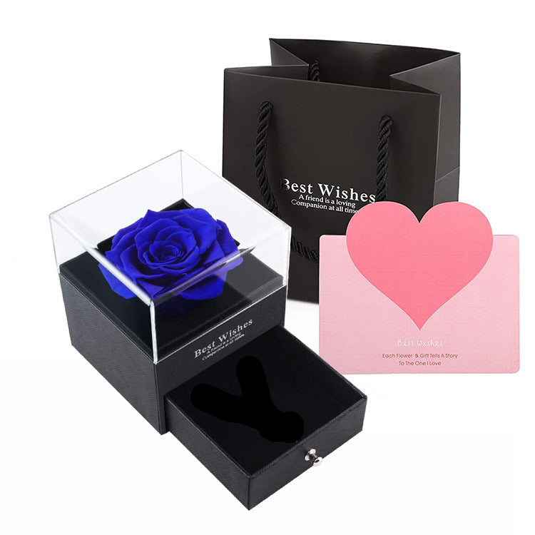 Black gift box with a blue rose, black gift bag, and pink card on a white background