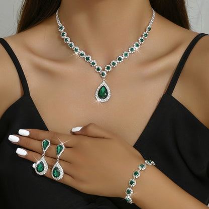 Green gemstone jewelry set including necklace, earrings, and bracelet on a model wearing a black top.